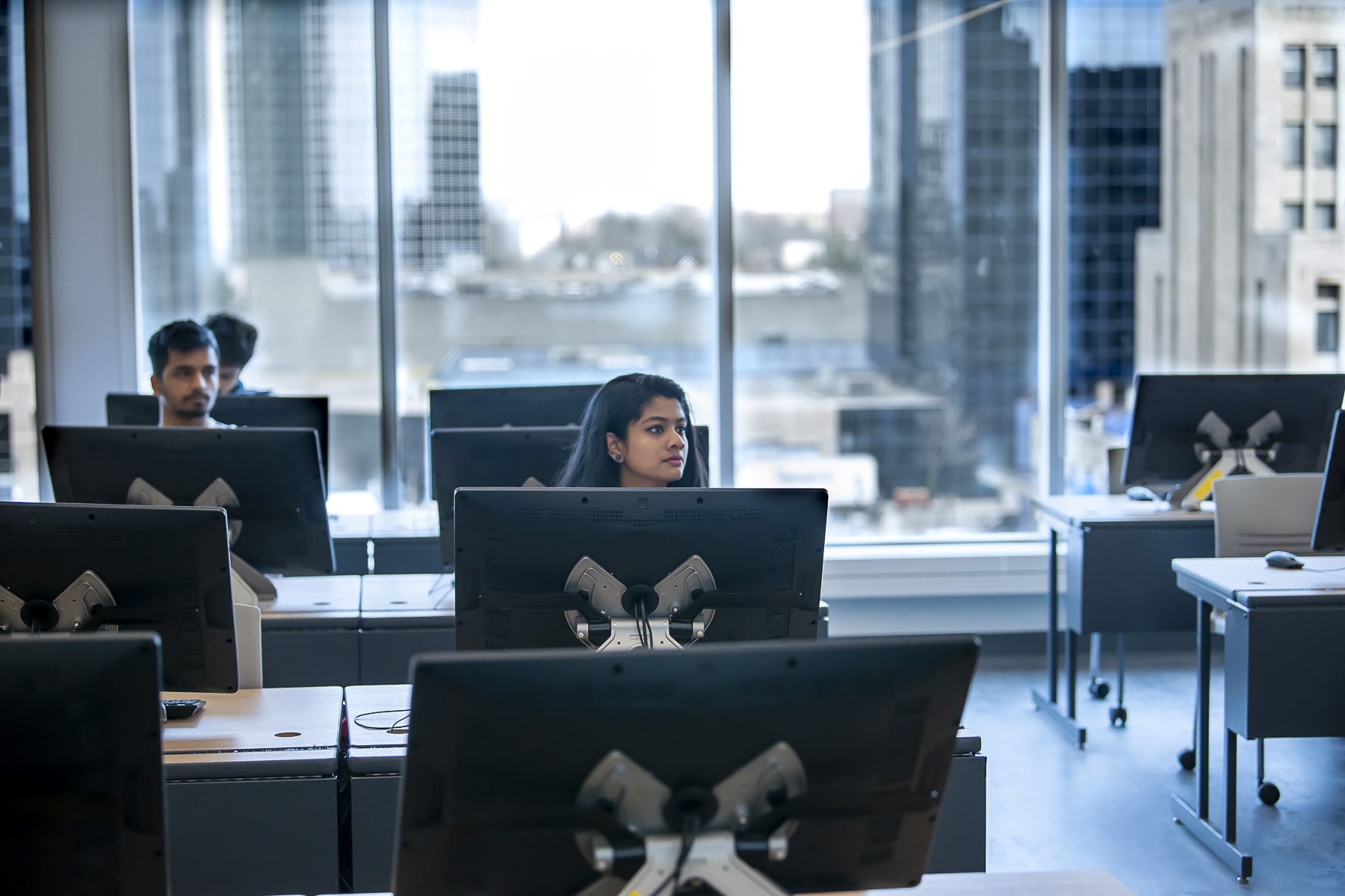 student sits at desk with large computer monitor in a classroom