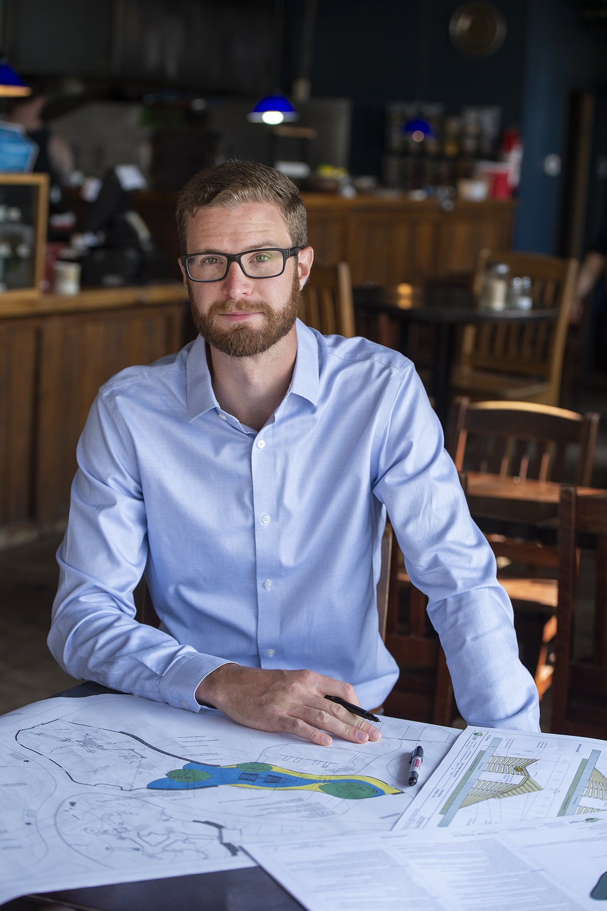 Alumni Success Stories Alex Waffle sits at table with environmental design paperworks