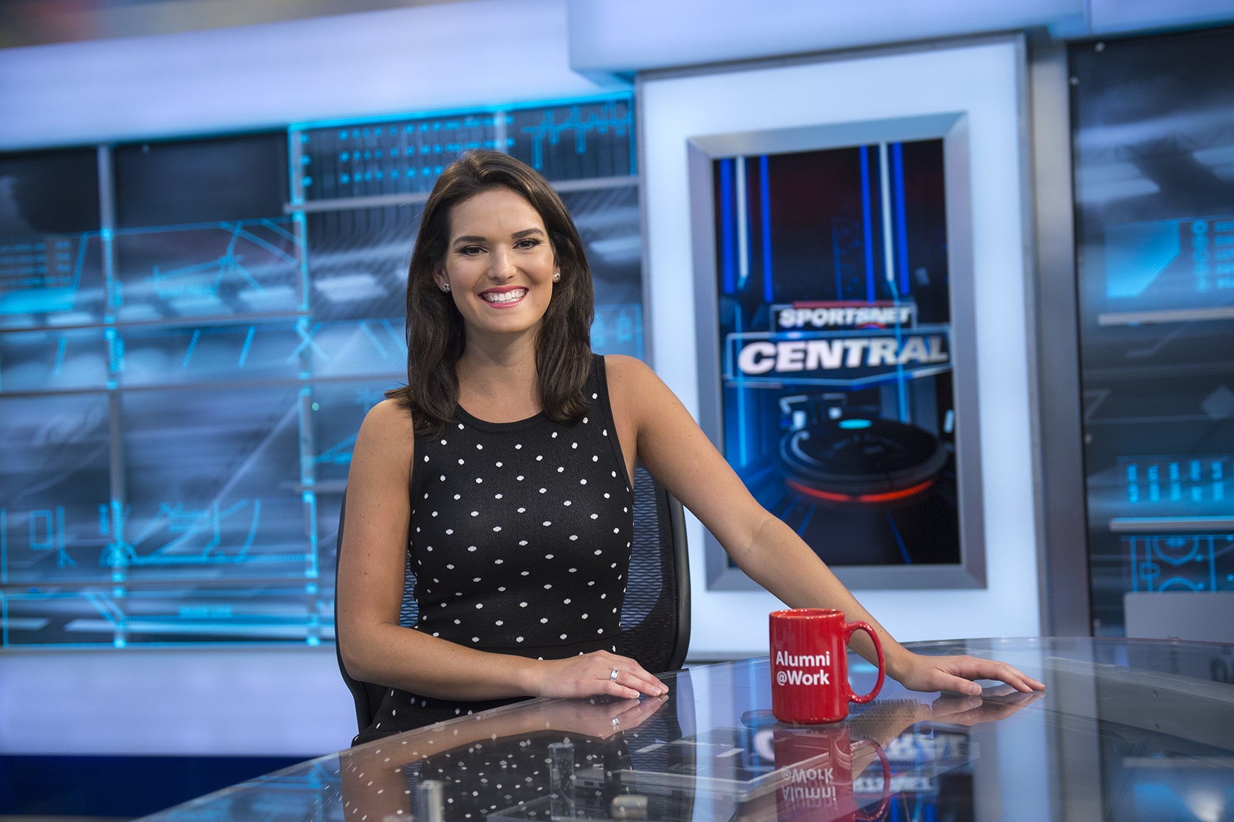 Explore Alumni Stories Caroline Cameron smiles from behind desk on Sportsnet