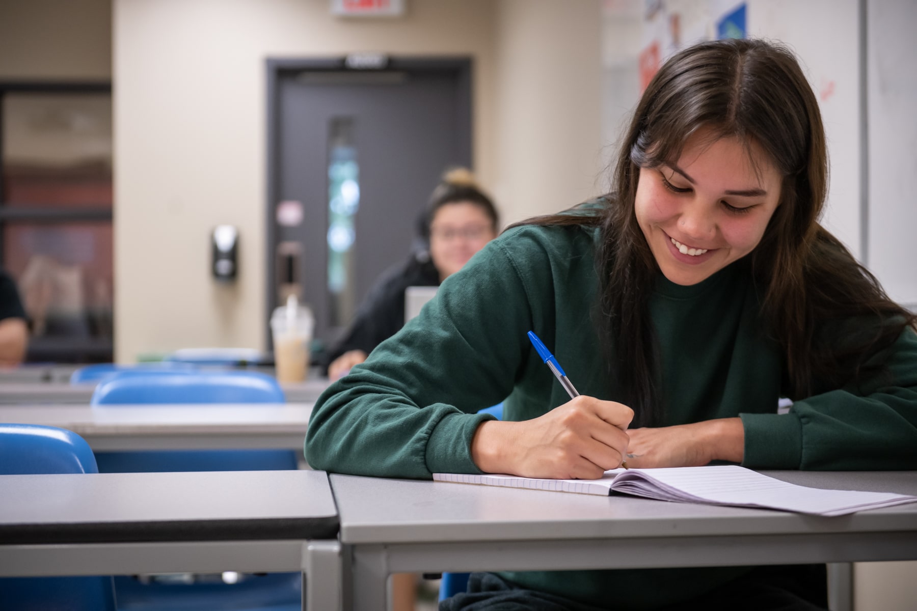 Summer College person smiling while writing in notebook