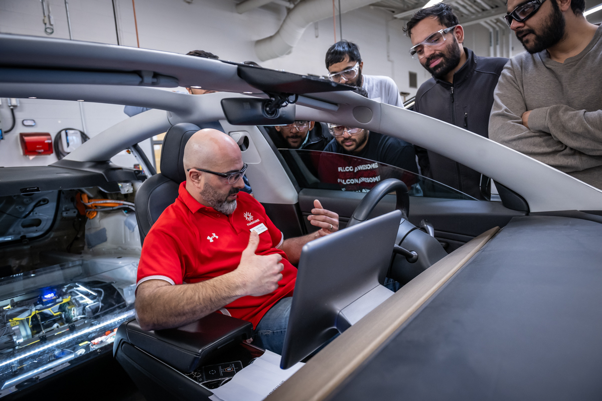 A Fanshawe instructor speaks to students while seated in a Tesla.