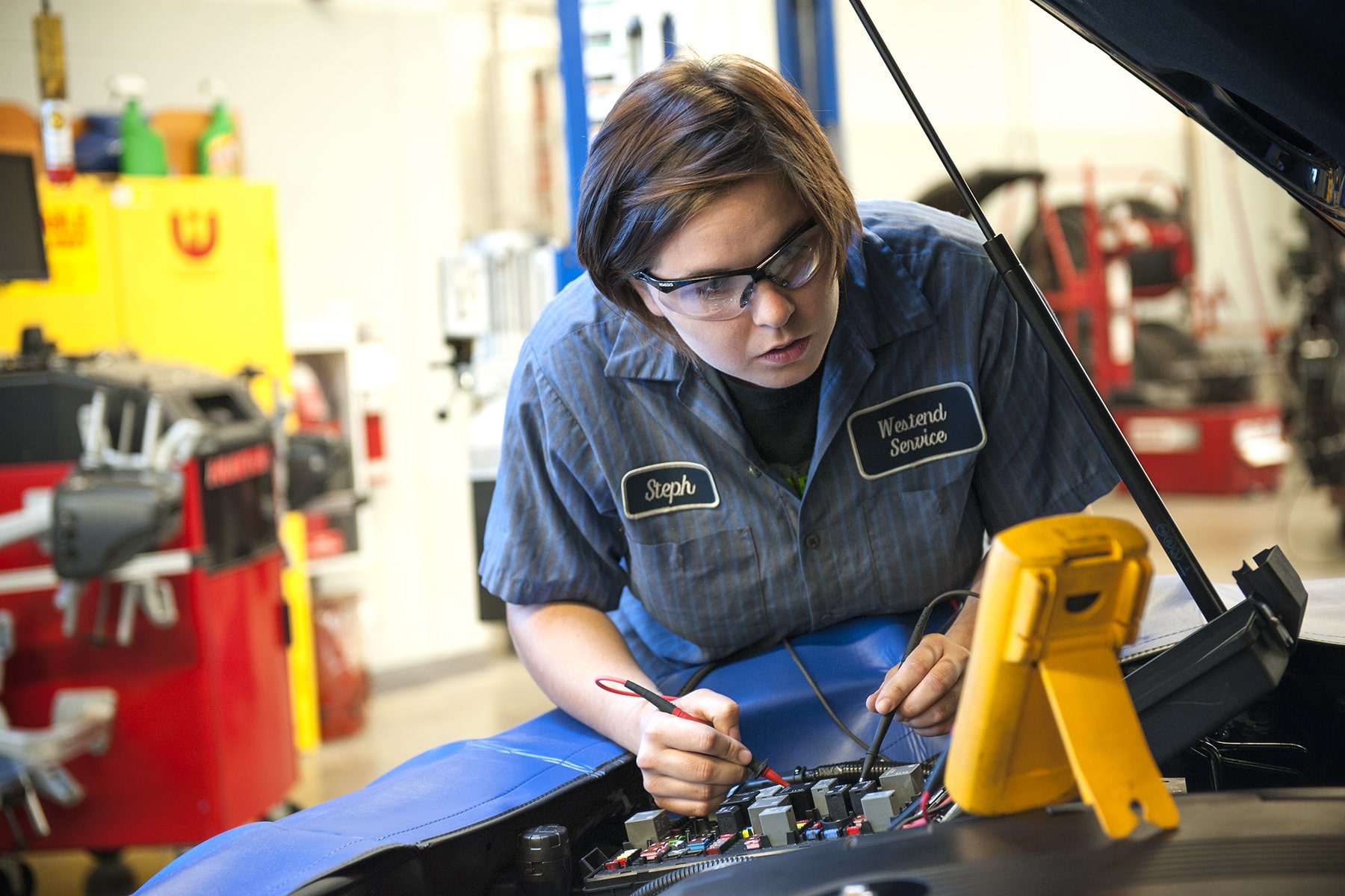person testing electronics under the hood of a car