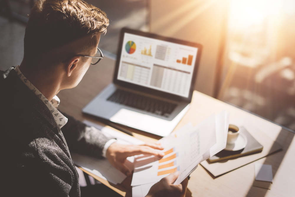 Employee reviewing spreadsheet and graphs