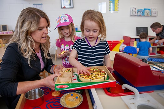 Childhood Educators and Assistants childhood educator sits with students while they play