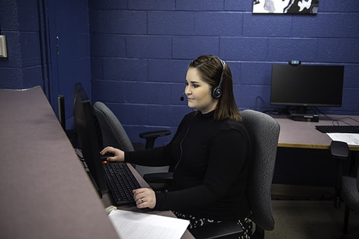 Administrative Officers administrative student sits at computer with headset on