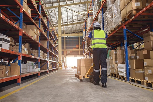 Material Handler person pushes boxes on a cart in a warehouse