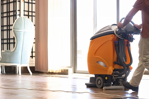 Light Duty Cleaner person pushes floor cleaner through hallway