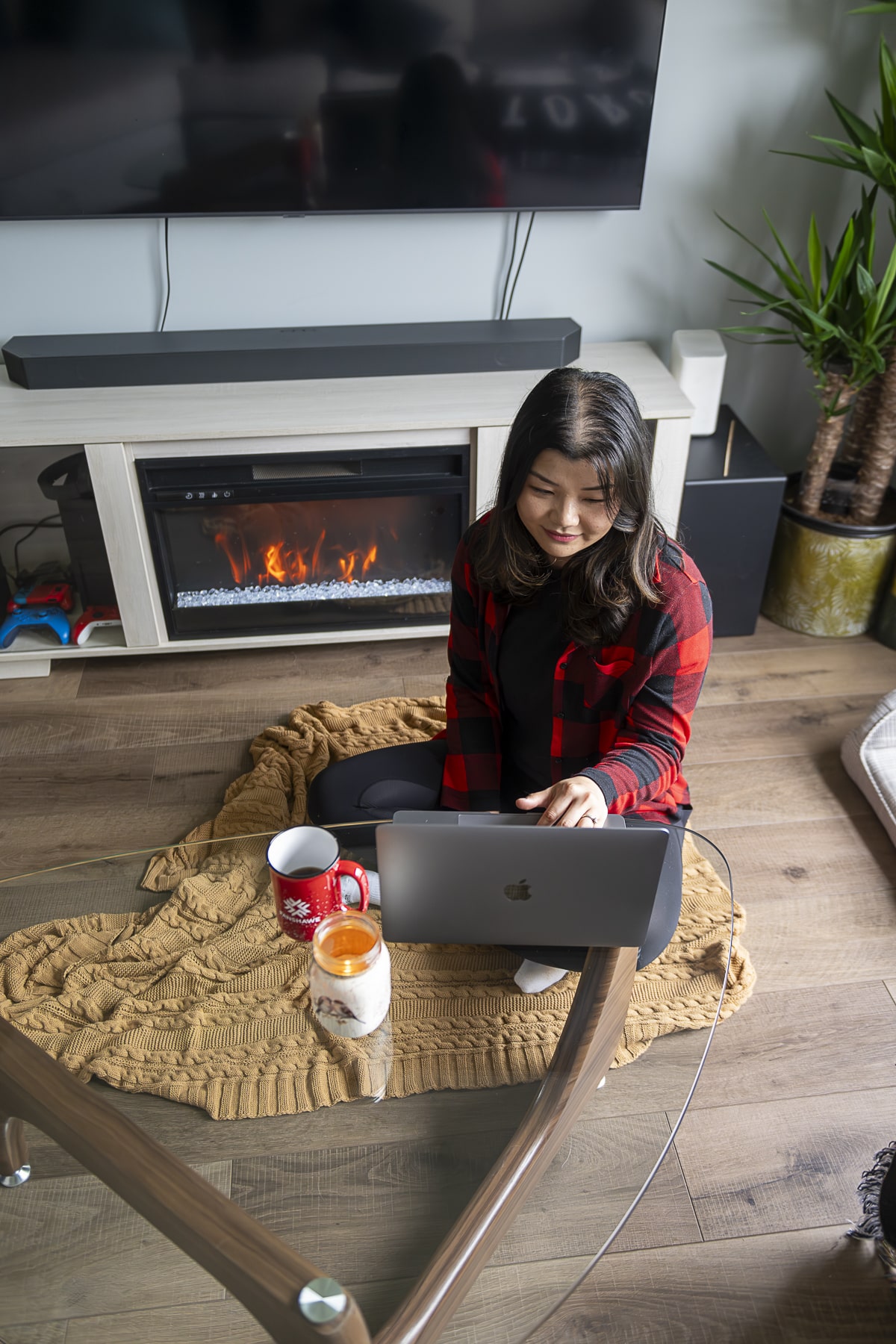 students sits by fireplace while studying on laptop