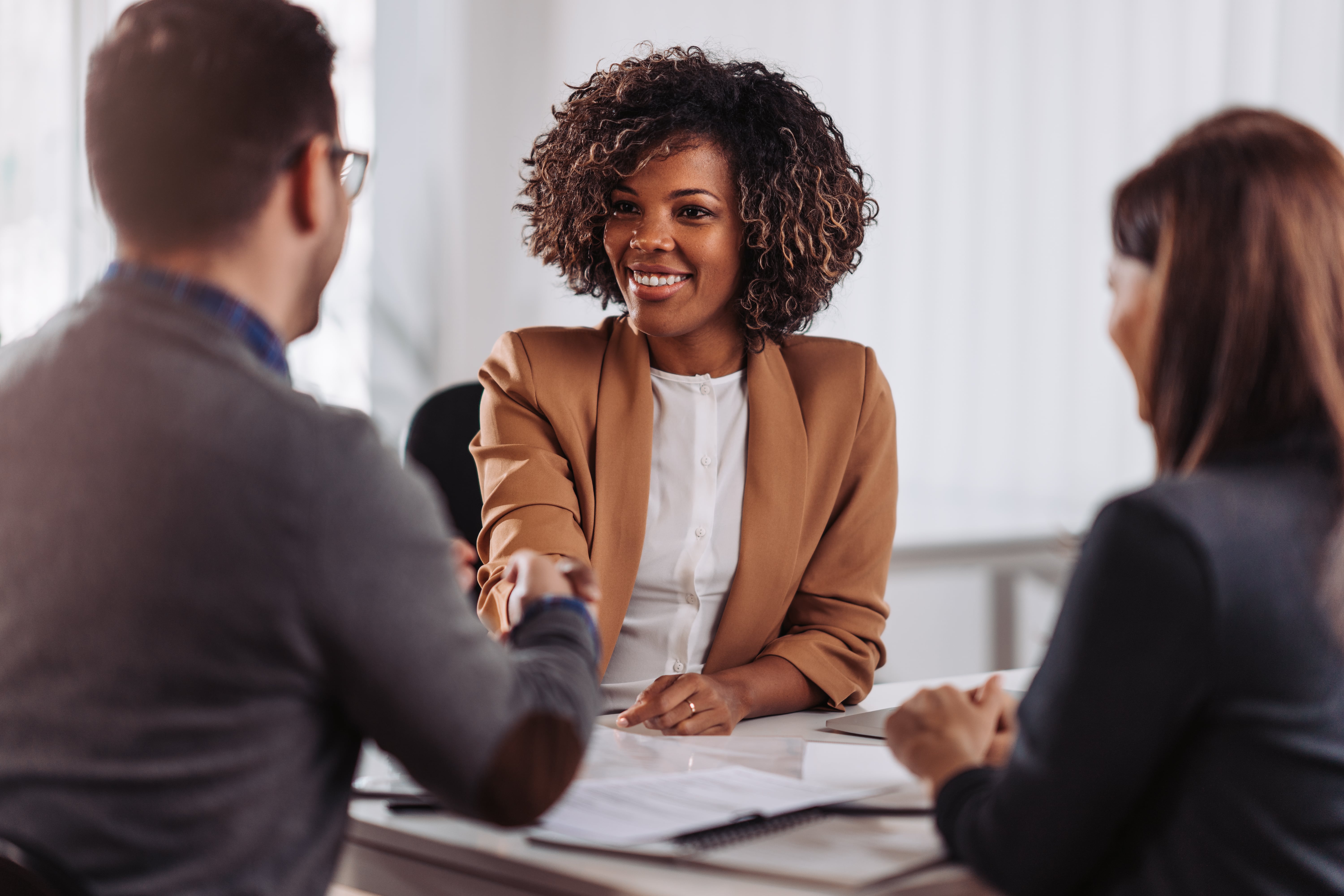Professionals shake hands over desk with paperwork