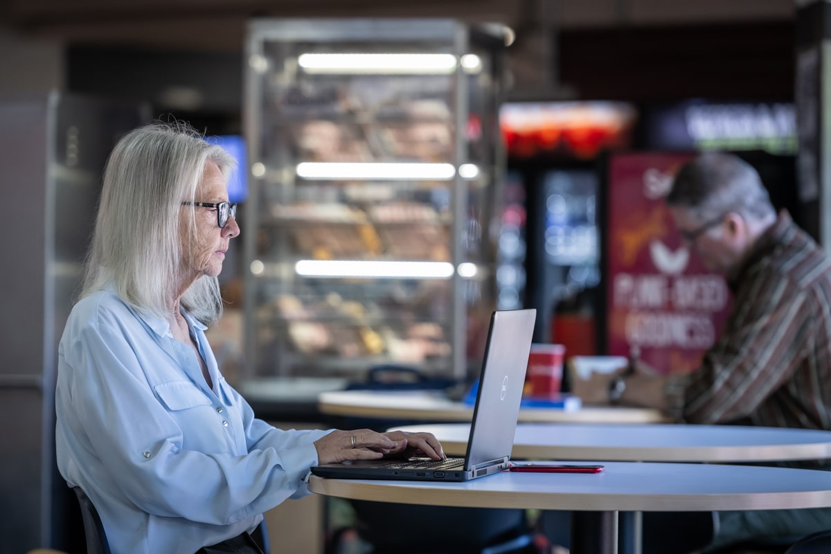 student sits at table in cafe while studying