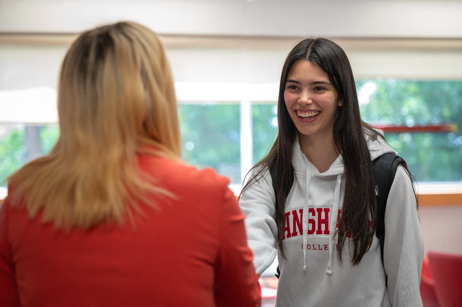 a student is shaking hand with a college staff
