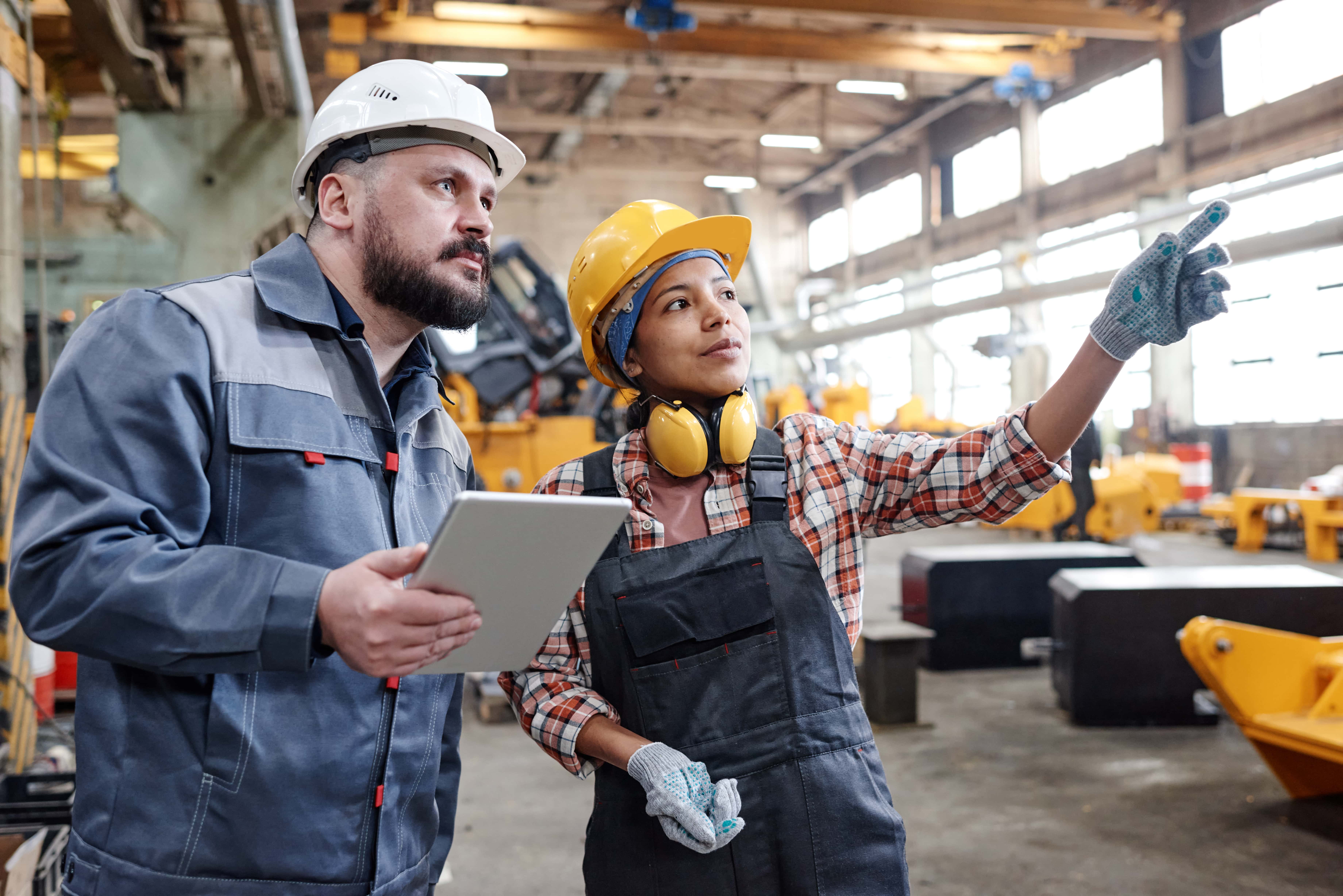 Industry Connections woman in hardhat points and talks as man listens