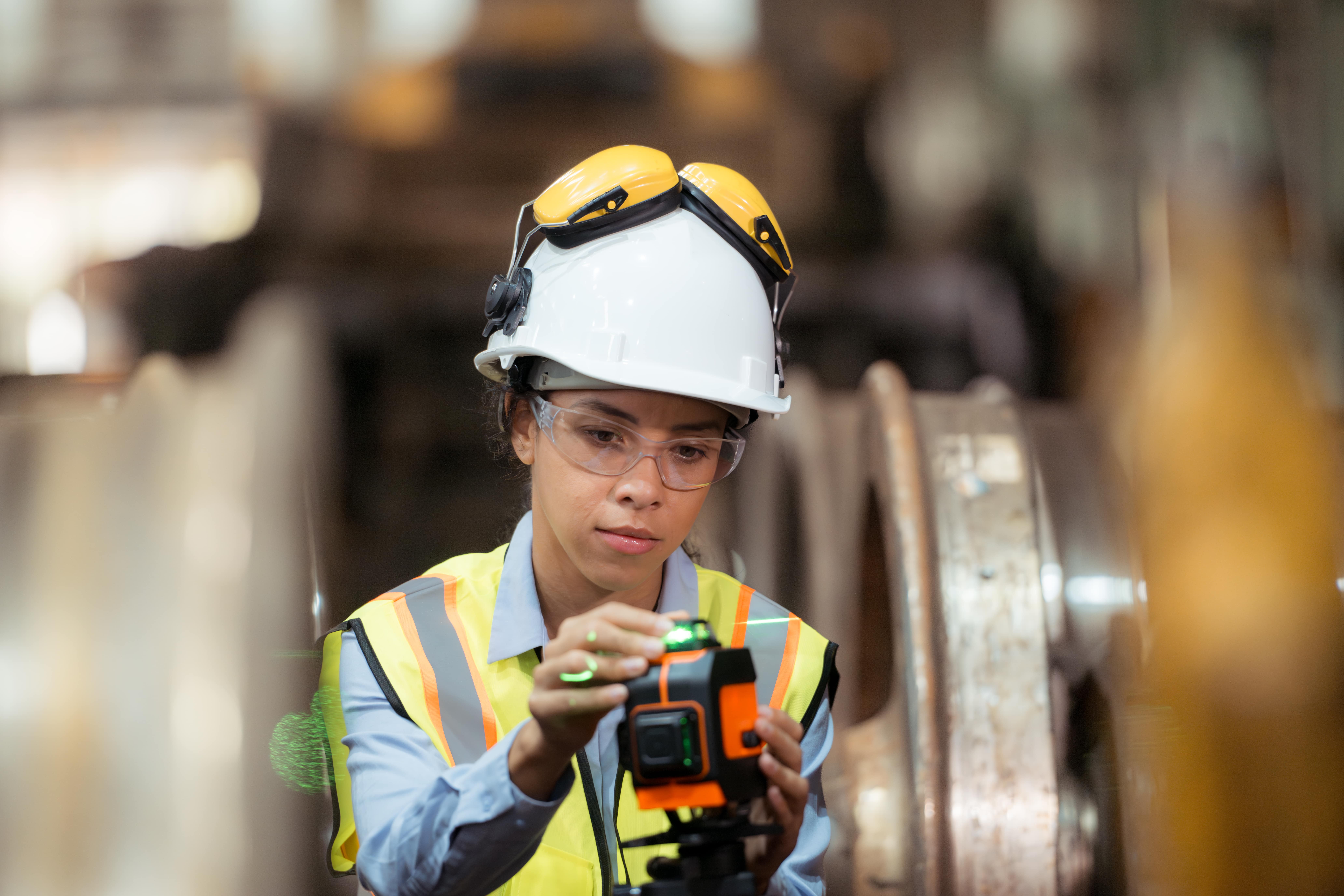 Connect, Mentor, Transform woman in hard hat configures tool