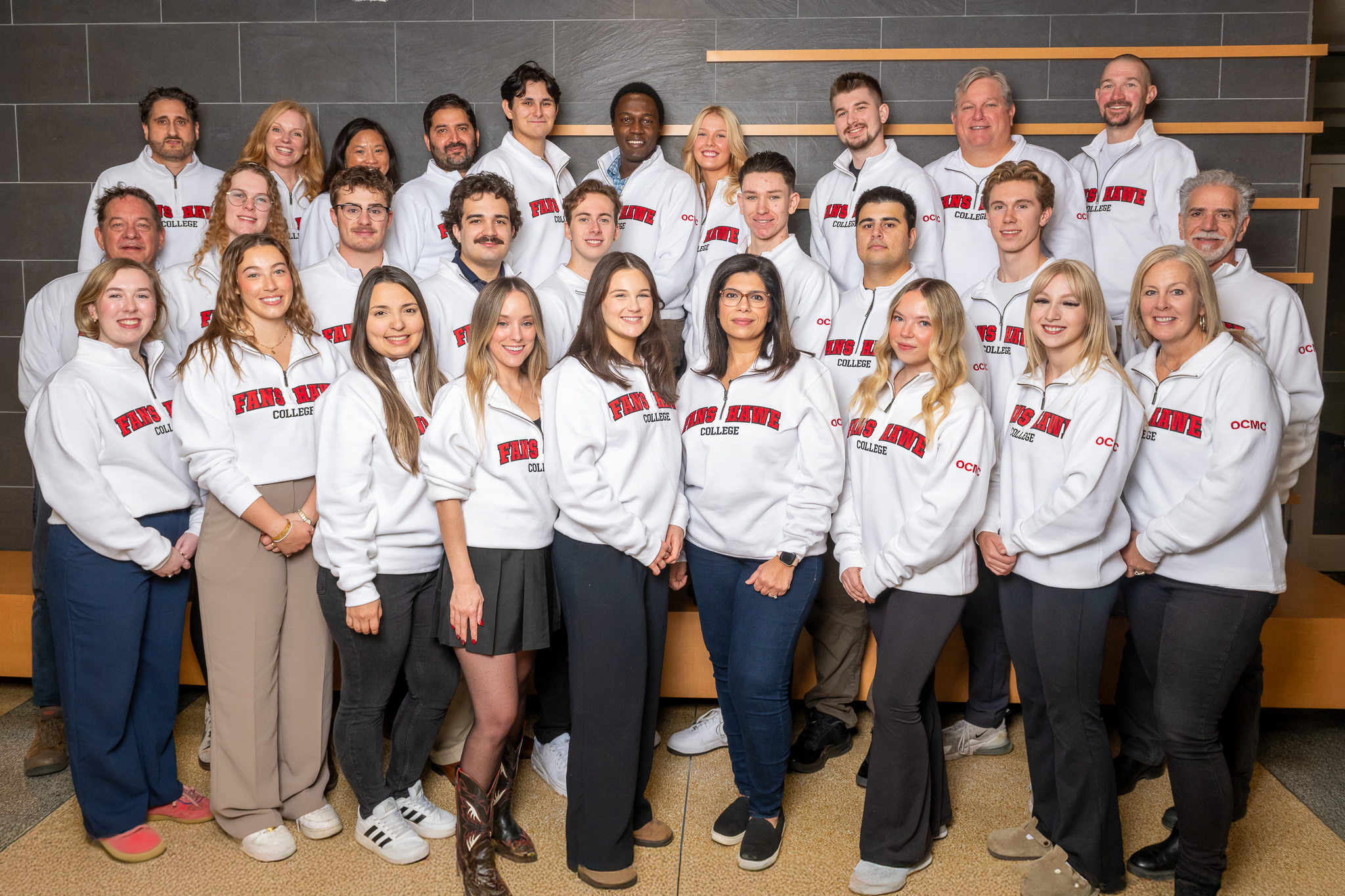 Students in white Fanshawe sweaters posting for a group photo.
