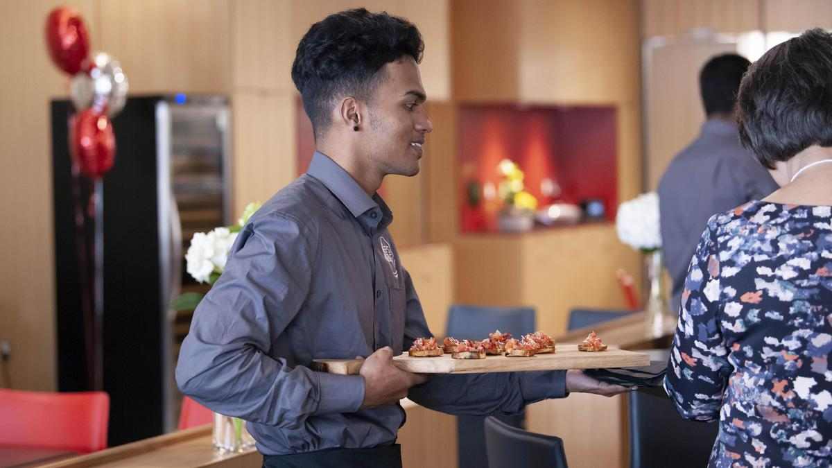 server carries a tray of food to customers