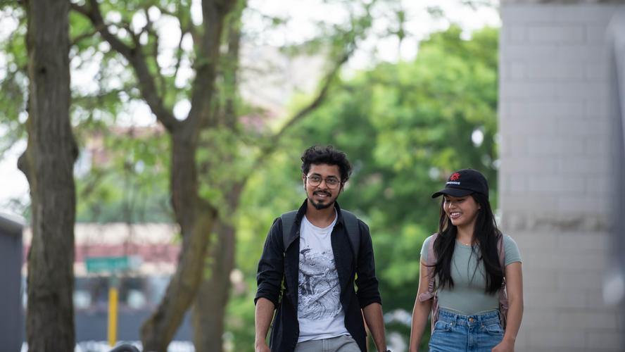 two students walk on campus together, smiling
