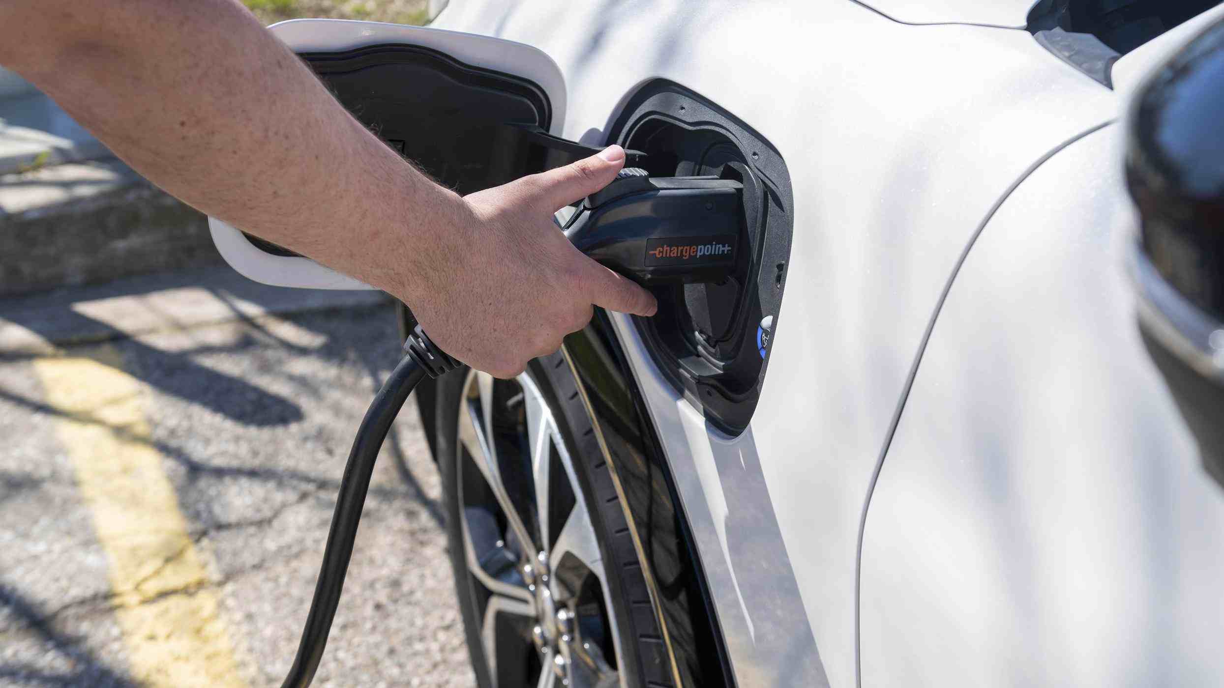 person plugs in Fanshawe's electric vehicle mustang