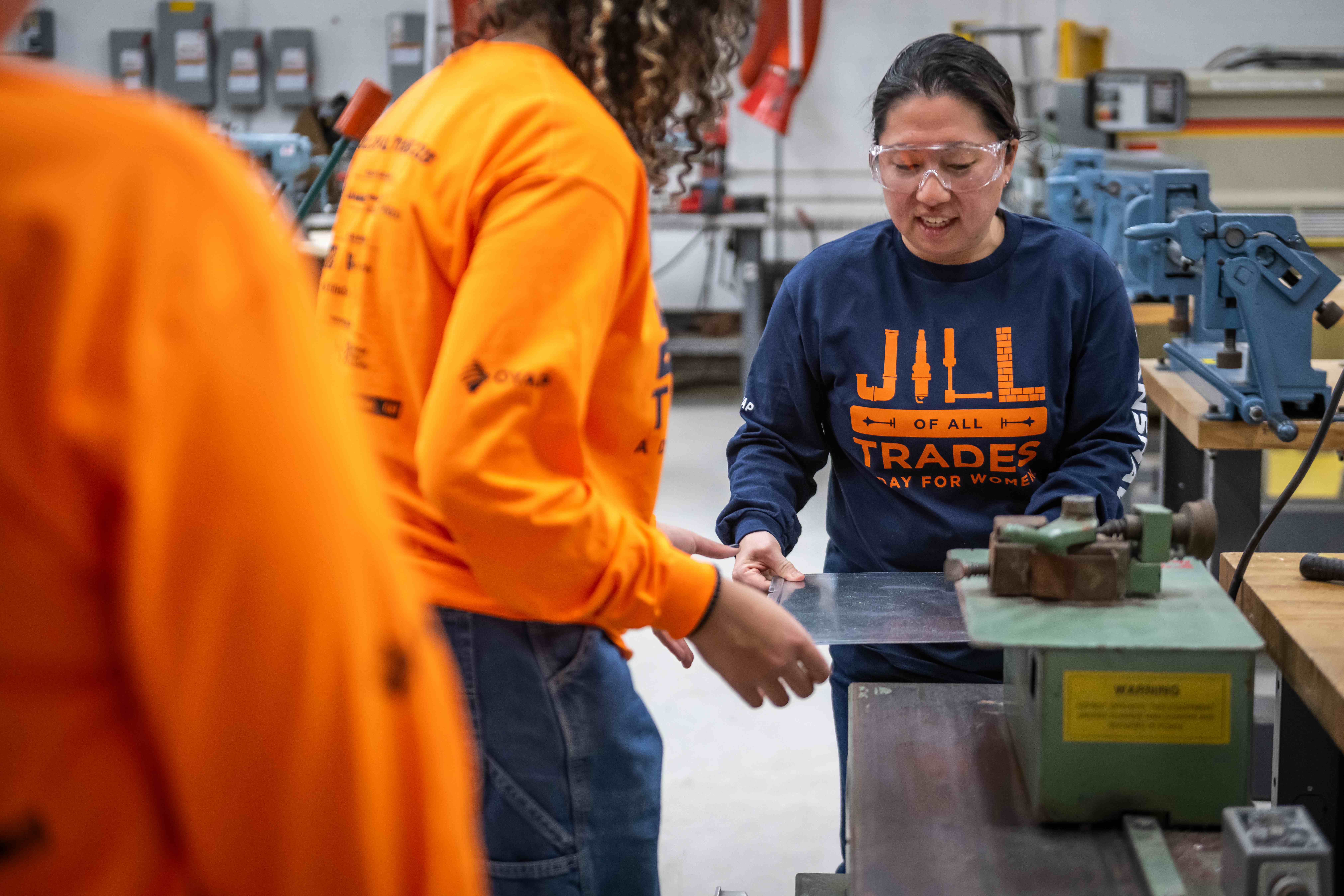 A female instructor guides a high school student through an activity during a Jill of All Trades event.