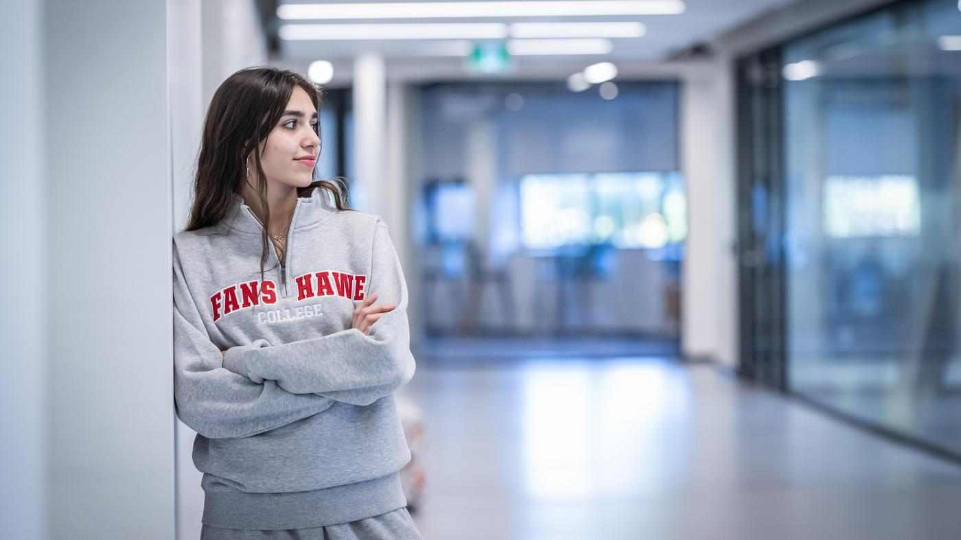 student stands in hallways at Fanshawe, wearing Fanshawe sweater