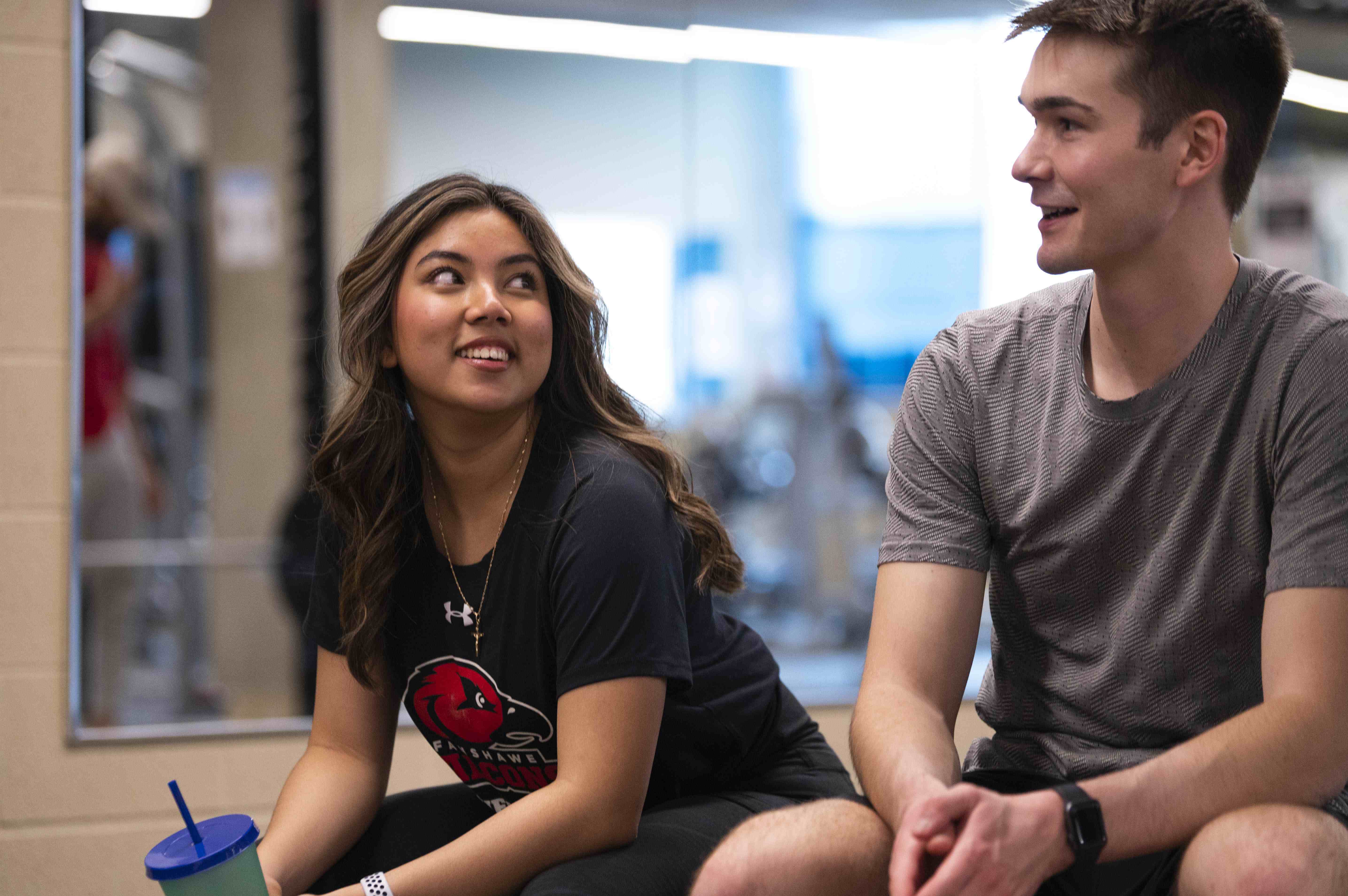 Two students speaking to one another while at the student wellness centre gym