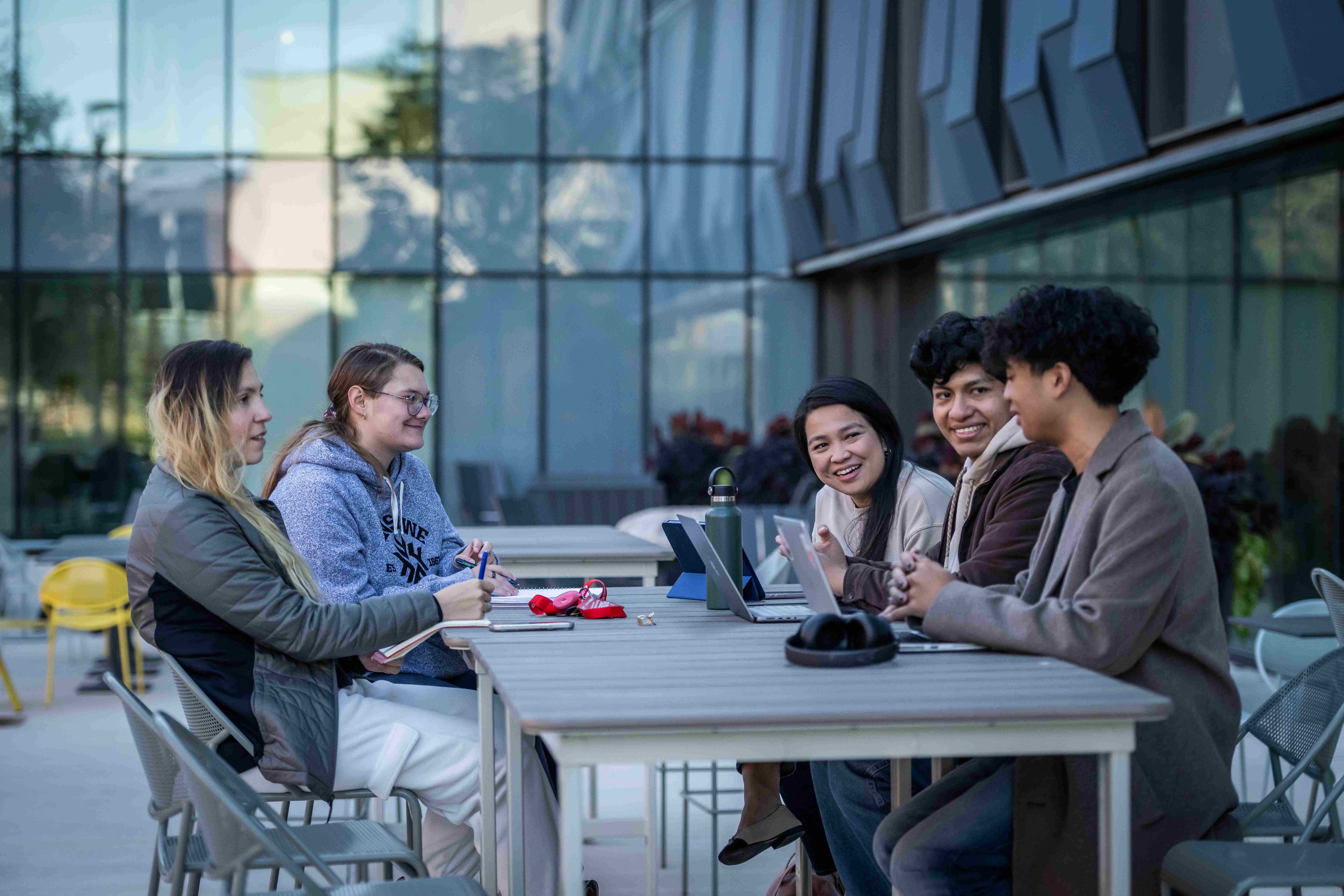 Five Fanshawe students sitting at a table outside of innovation village