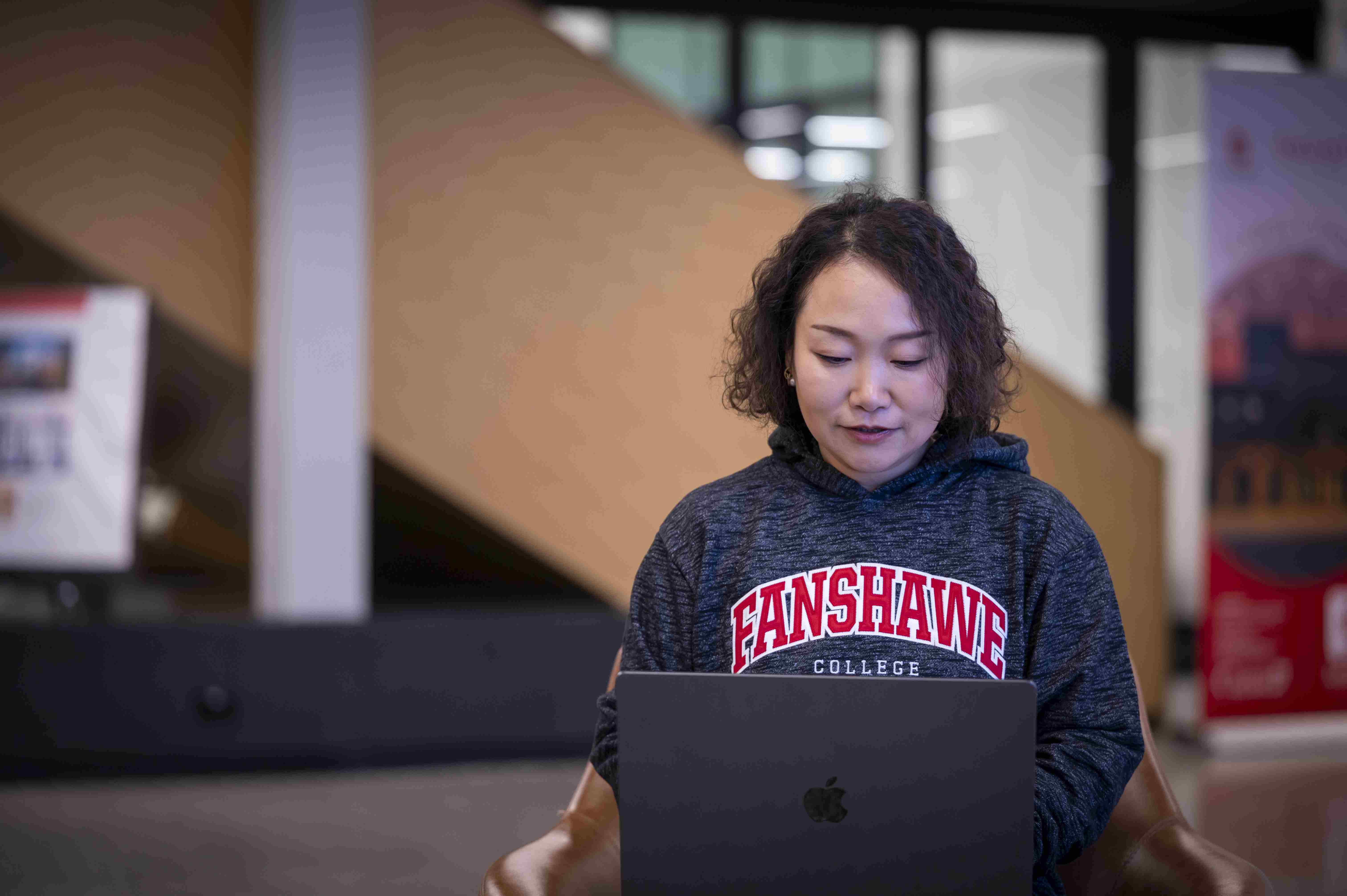 A student sitting in innovation village on their laptop