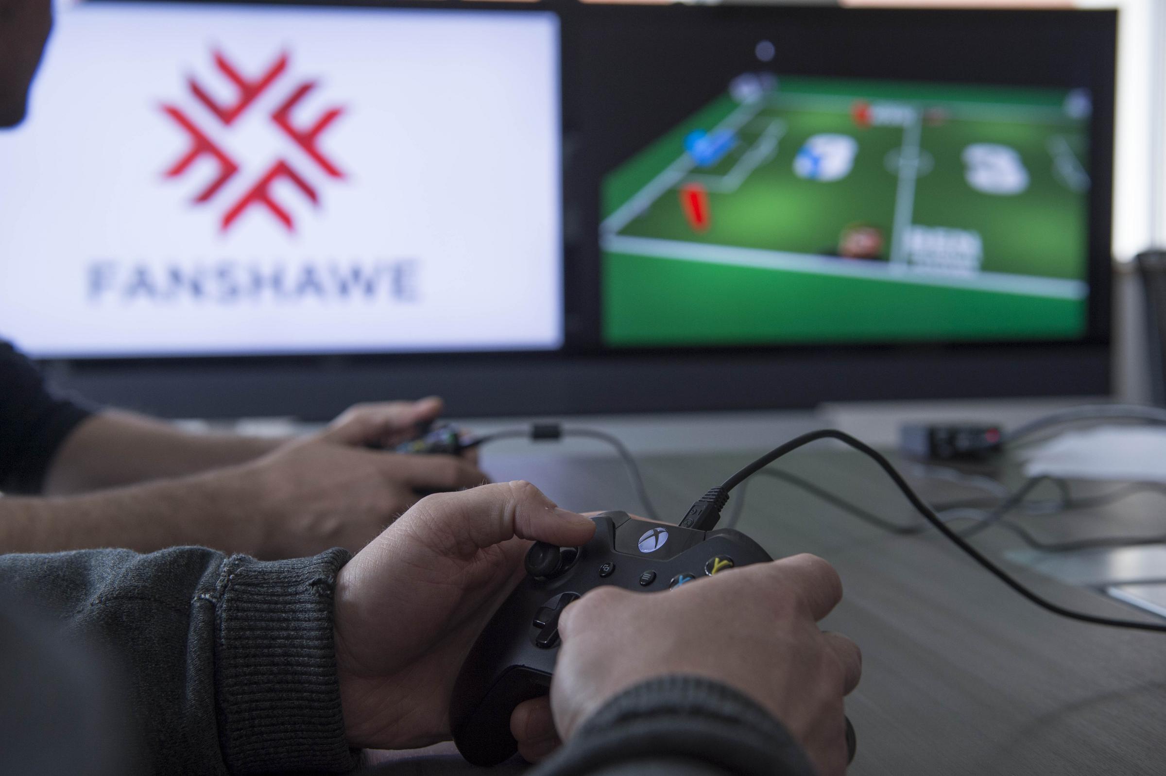 Hands holding an xbox controller with the screen in the background
