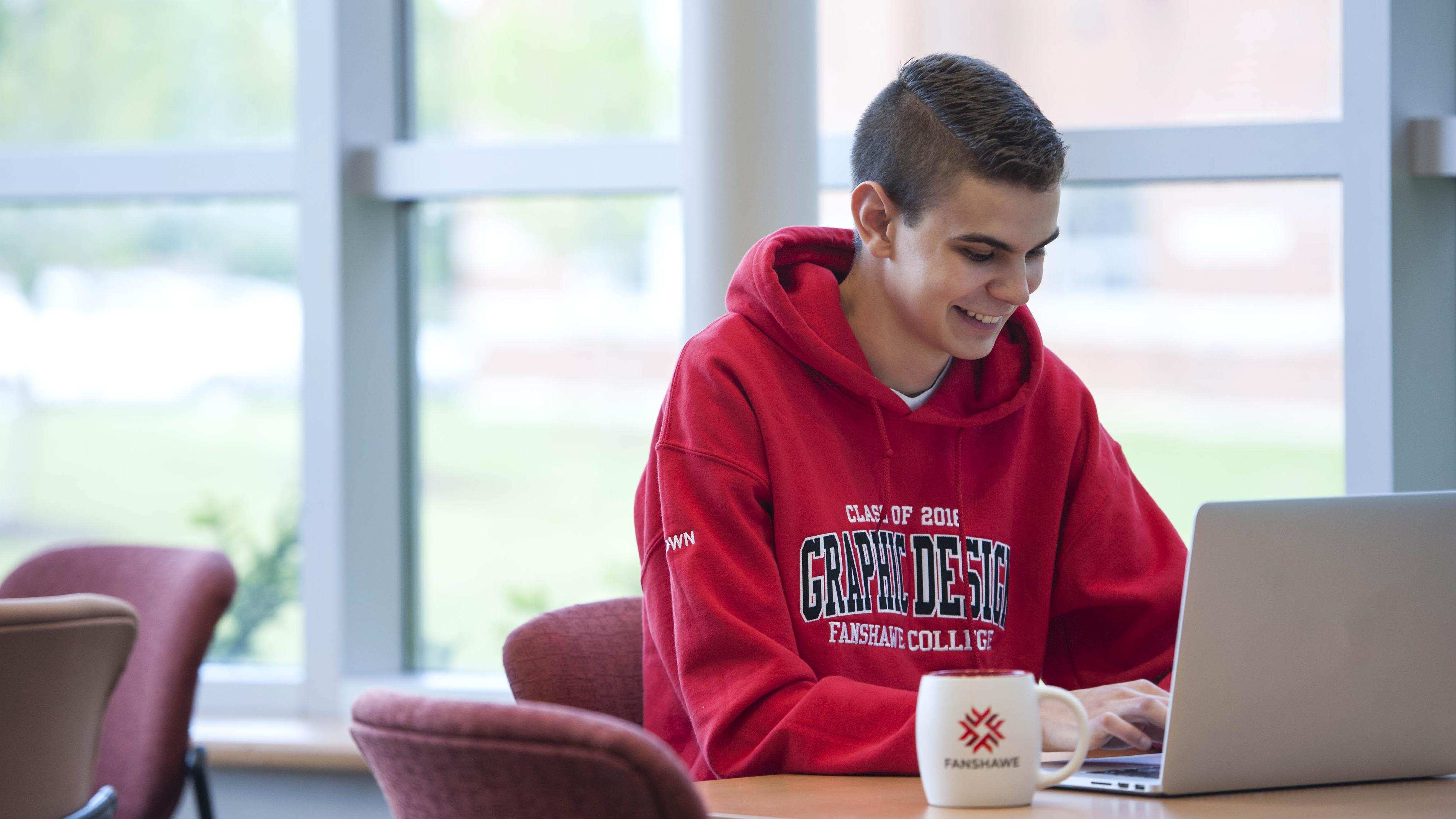 A student sitting in the cafeteria working on their laptop