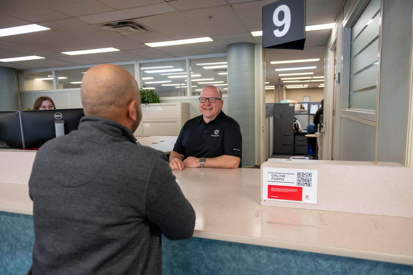 student talks to staff at office of the registrar desk