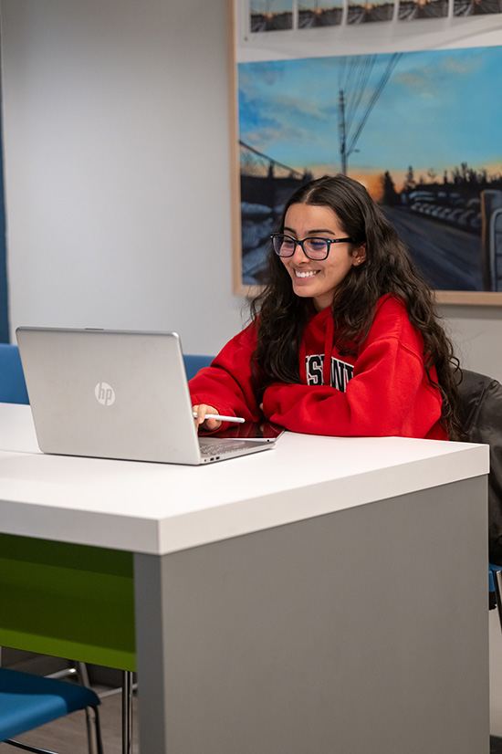 A students sitting at a desk smiling at their laptop