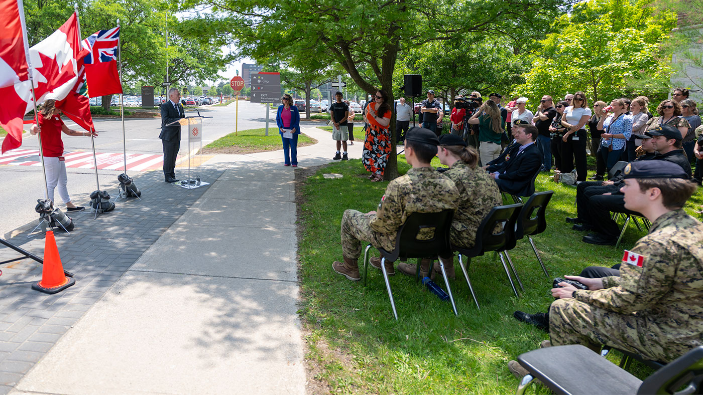 Peter Devlin speaks in front of crowd at military-connected college crosswalk opening
