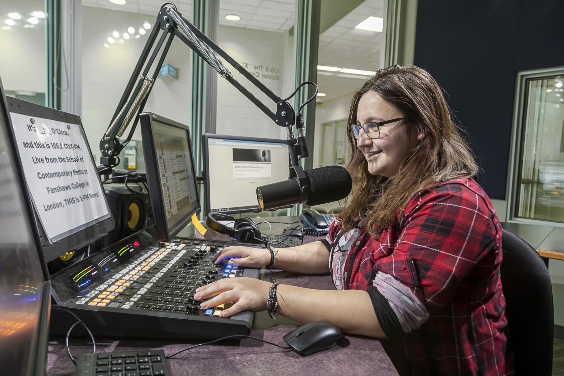 A student operates the audio board and speaks into a microphone in the 106.9 The X studio.
