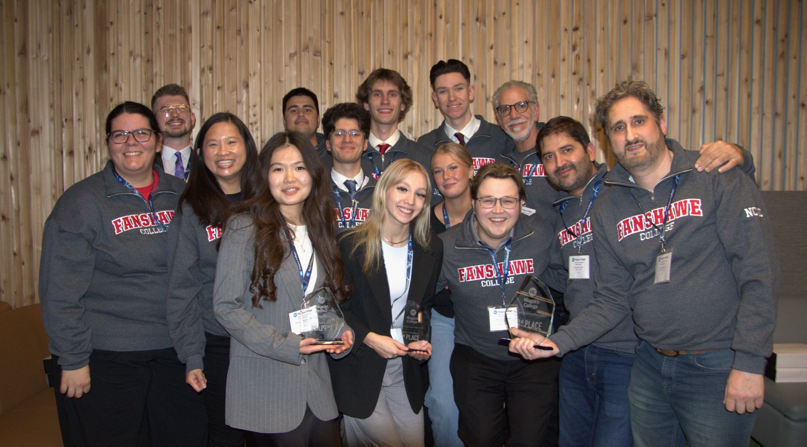 A group photo of smiling students and faculty holding first place trophies.