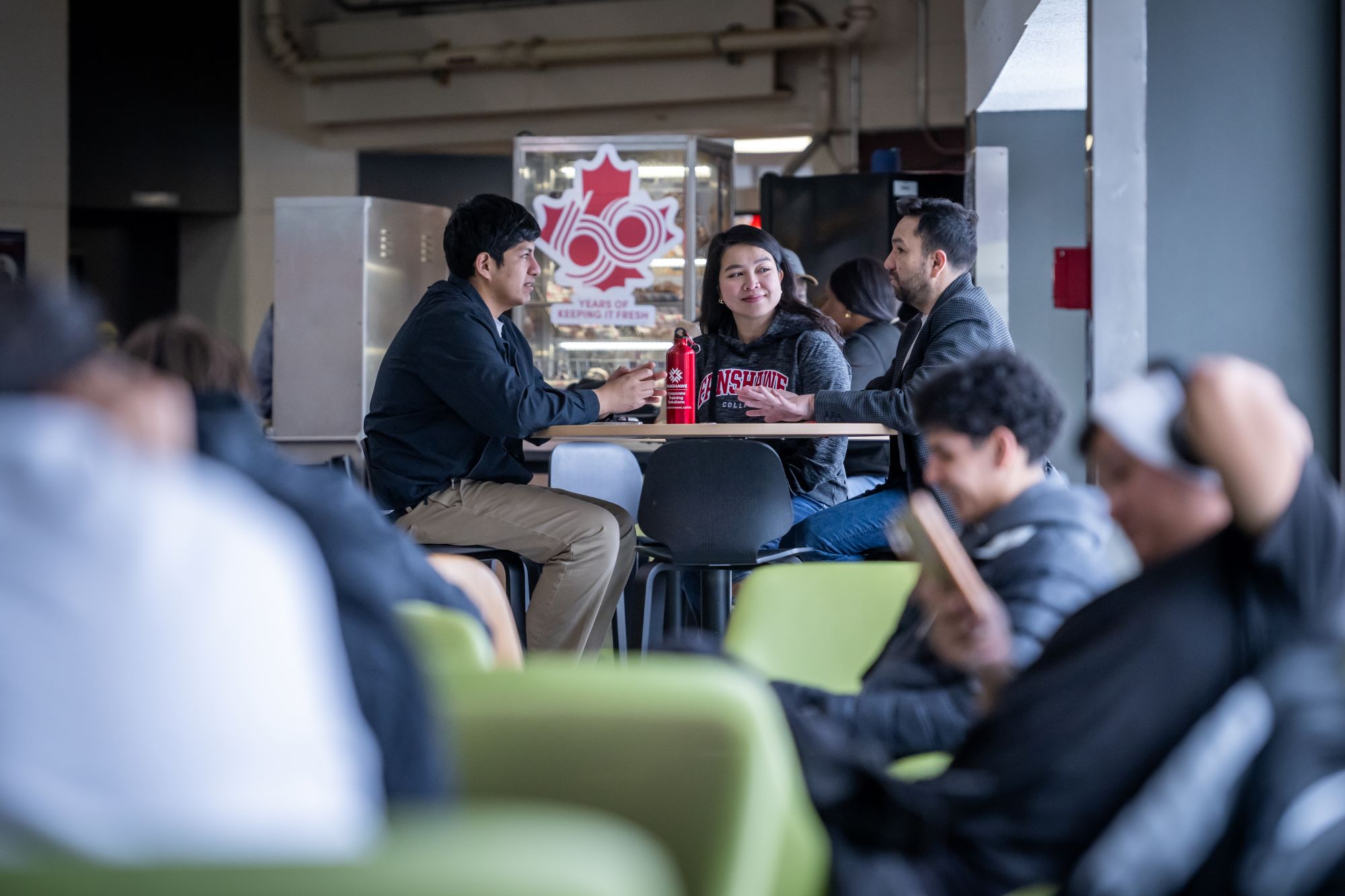 Three students sitting in a cafeteria at a table.
