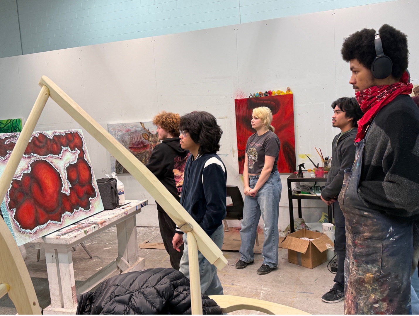 Students gather to examine a painted canvas with red and black shapes