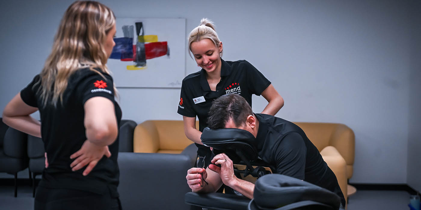At Fanshawe College's Open House, a prospective student receives a demonstration of massage therapy techniques from a student practitioner, while another student observes.