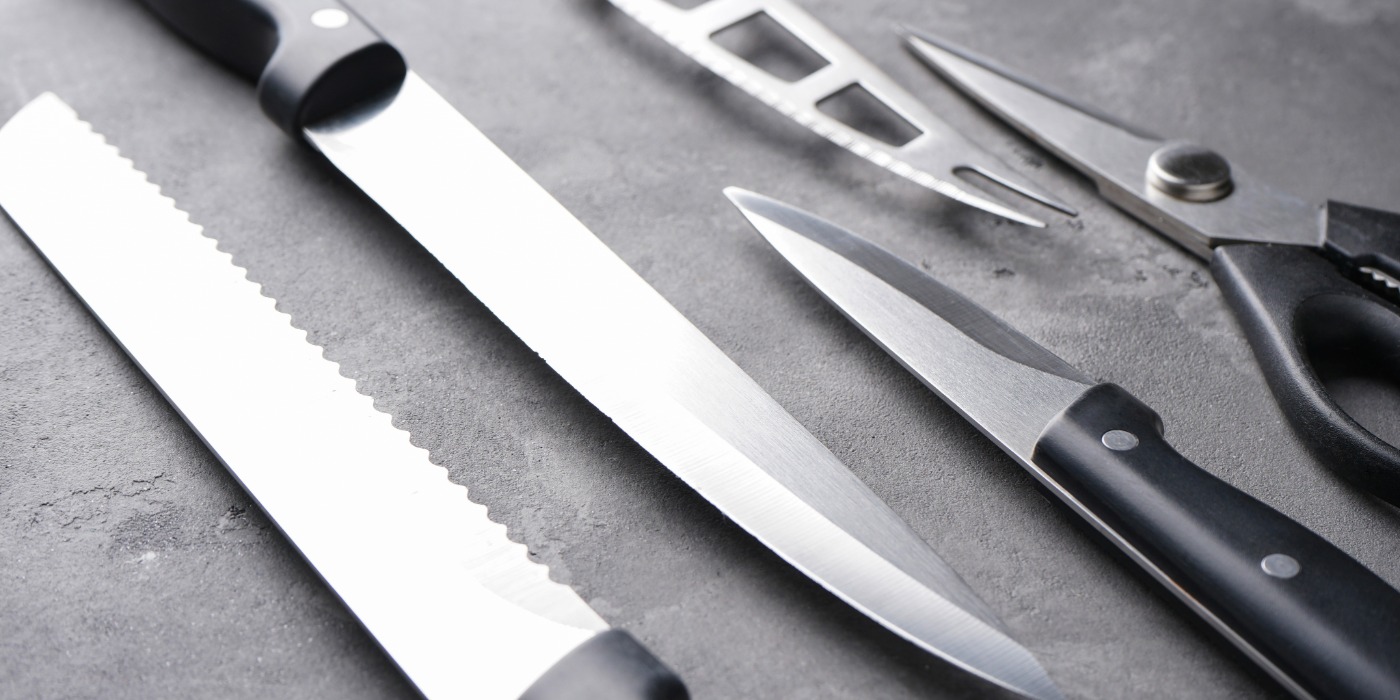 A bread knife, utility knife and paring knife, along with fish knife and scissors on a counter