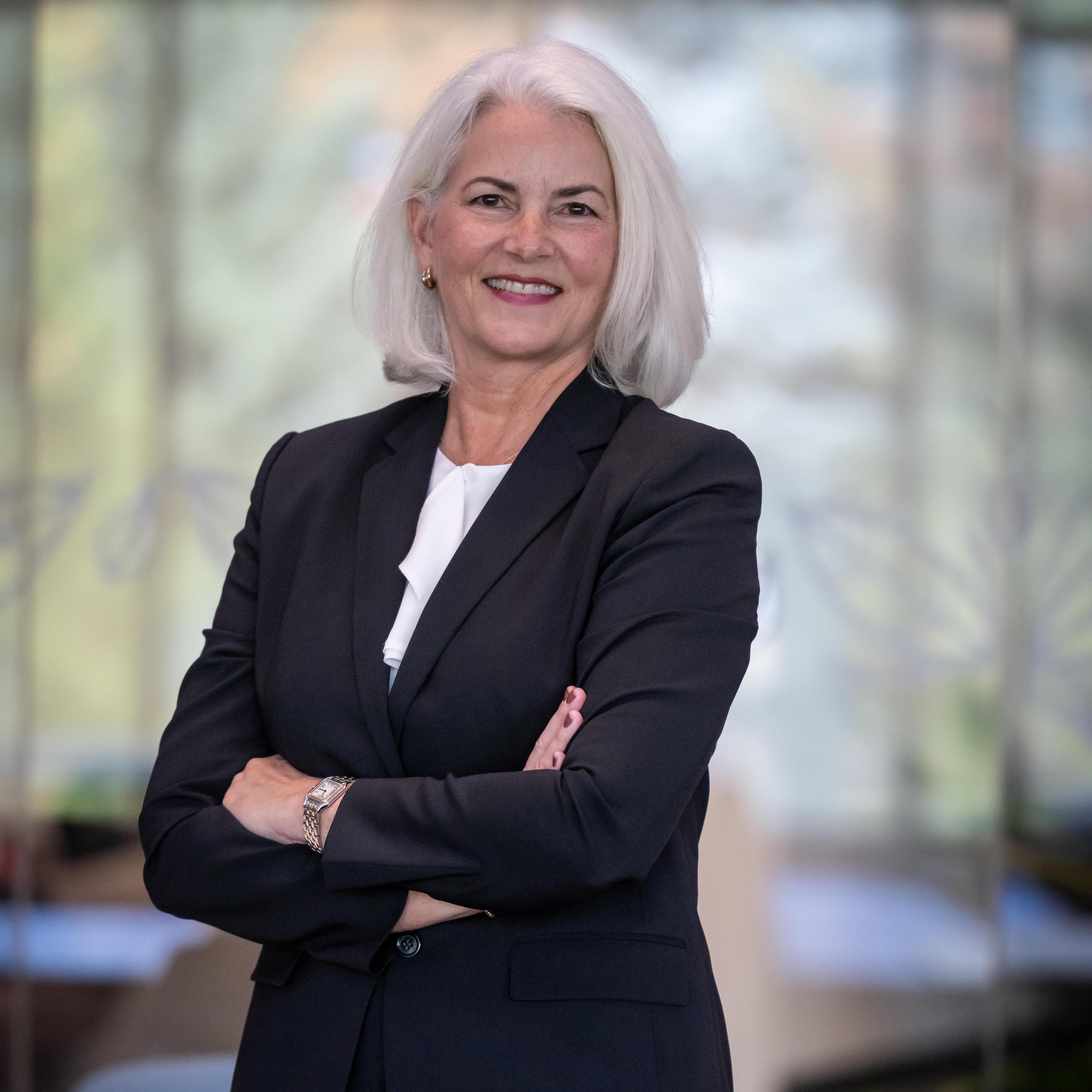 Image of Senior Vice President Susan Cluett standing and smiling with her arms crossed.
