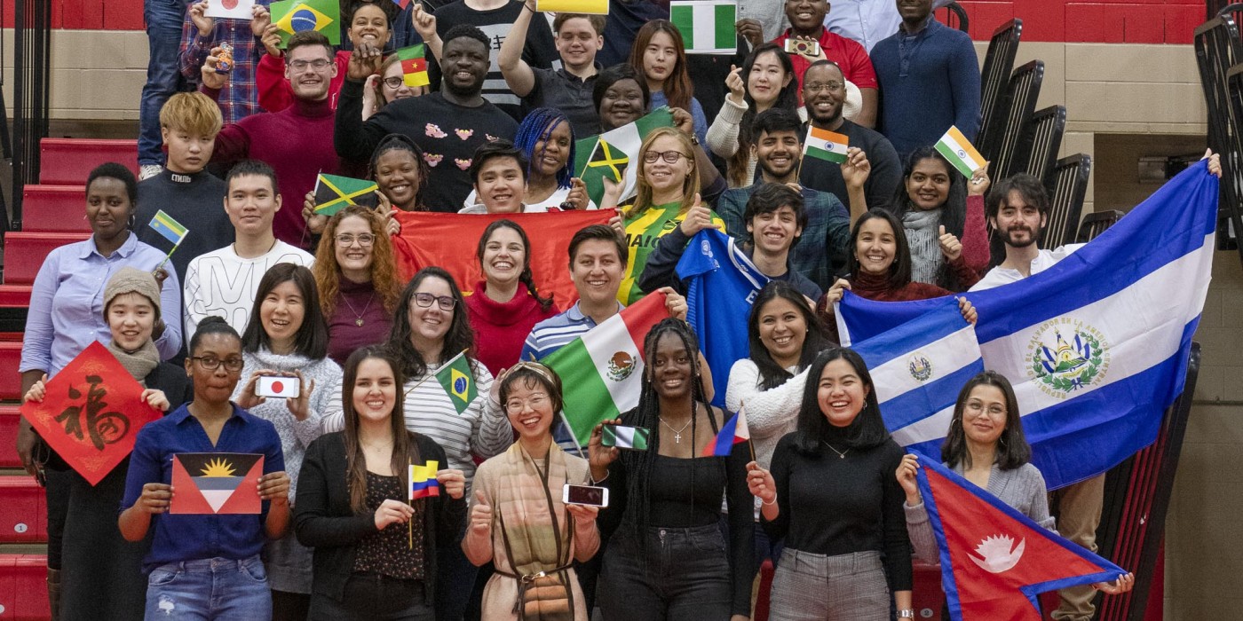 Group of International students at Fanshawe College, waving flags and smiling