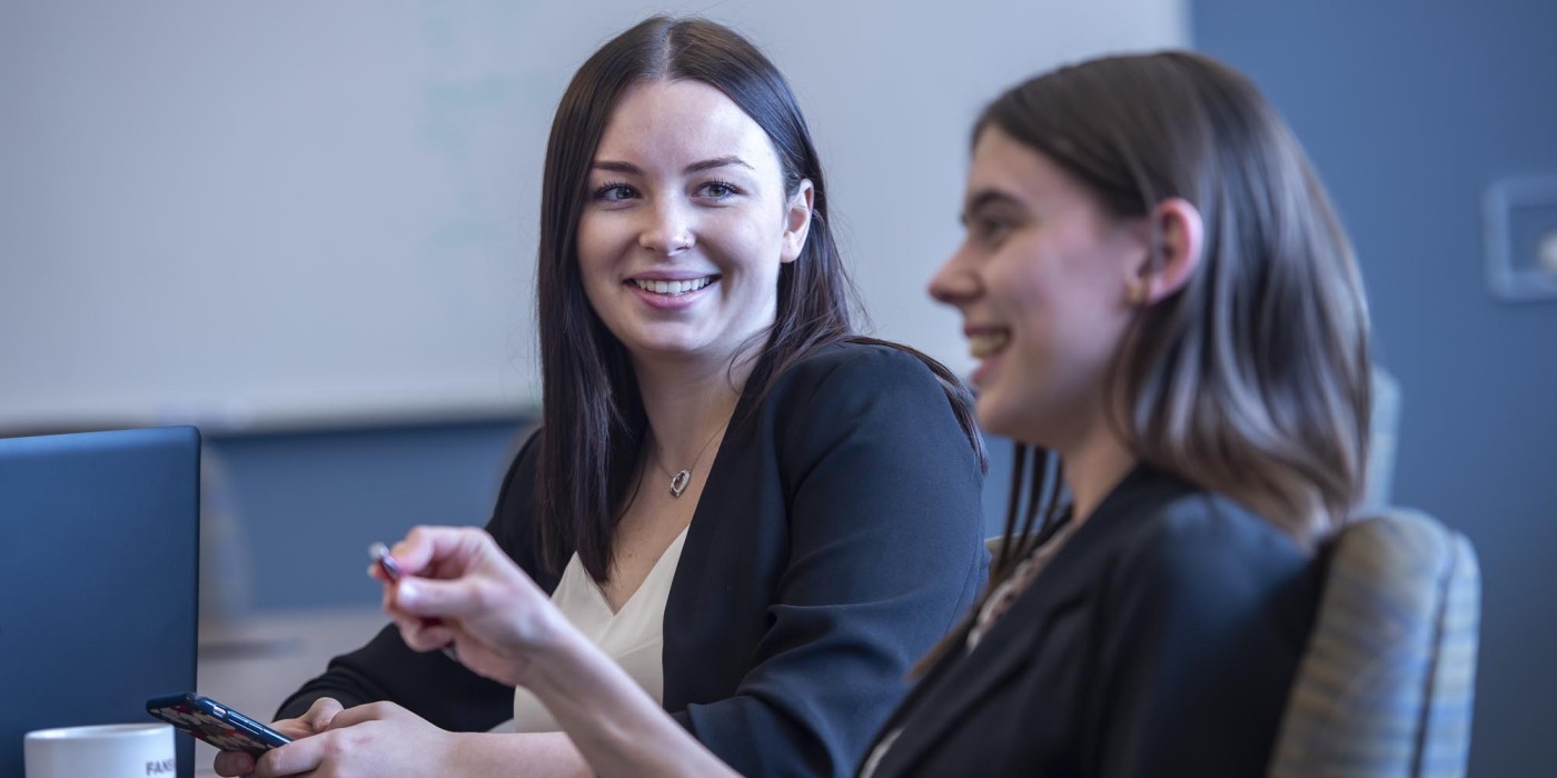 Two smiling Fanshawe business students, collaborating in a conference room