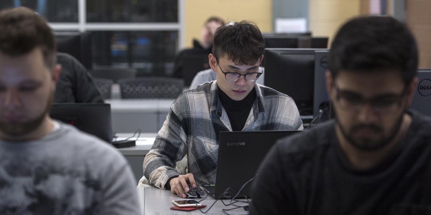 Cyber Security student, working on laptop in classroom lab setting