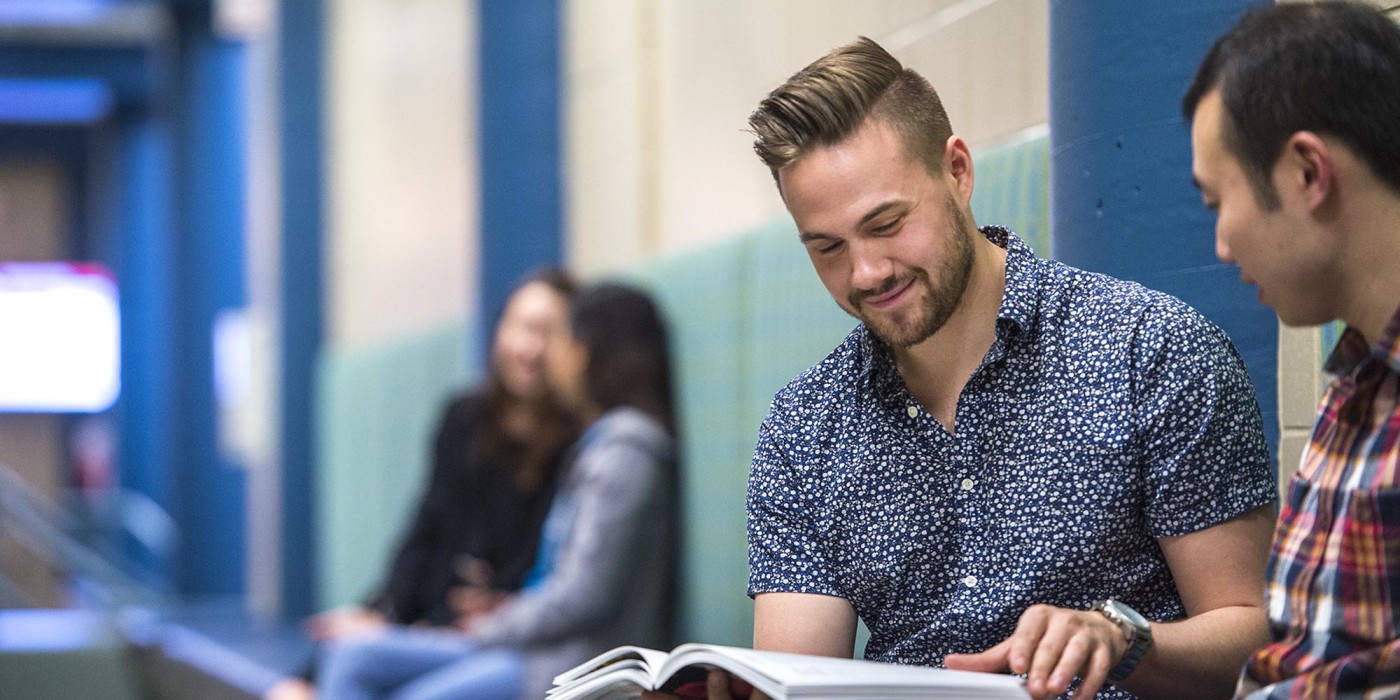 Fanshawe students sitting in hallway looking at textbook