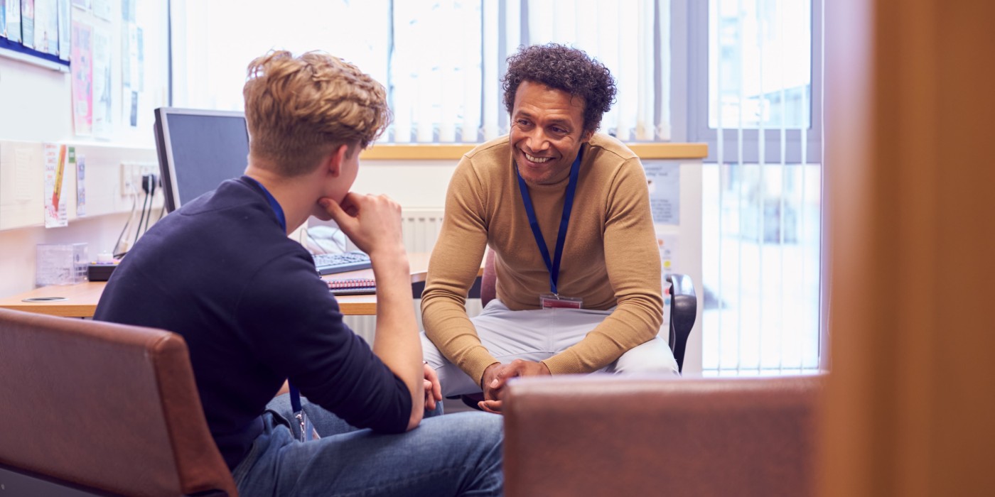 Man smiling at student while they talk in an office