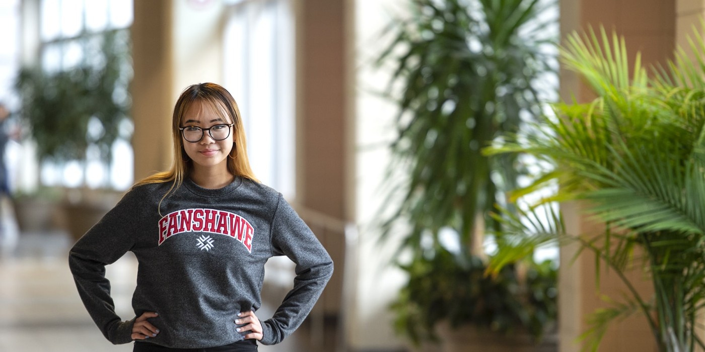 student standing in school hallway with hands on her hips