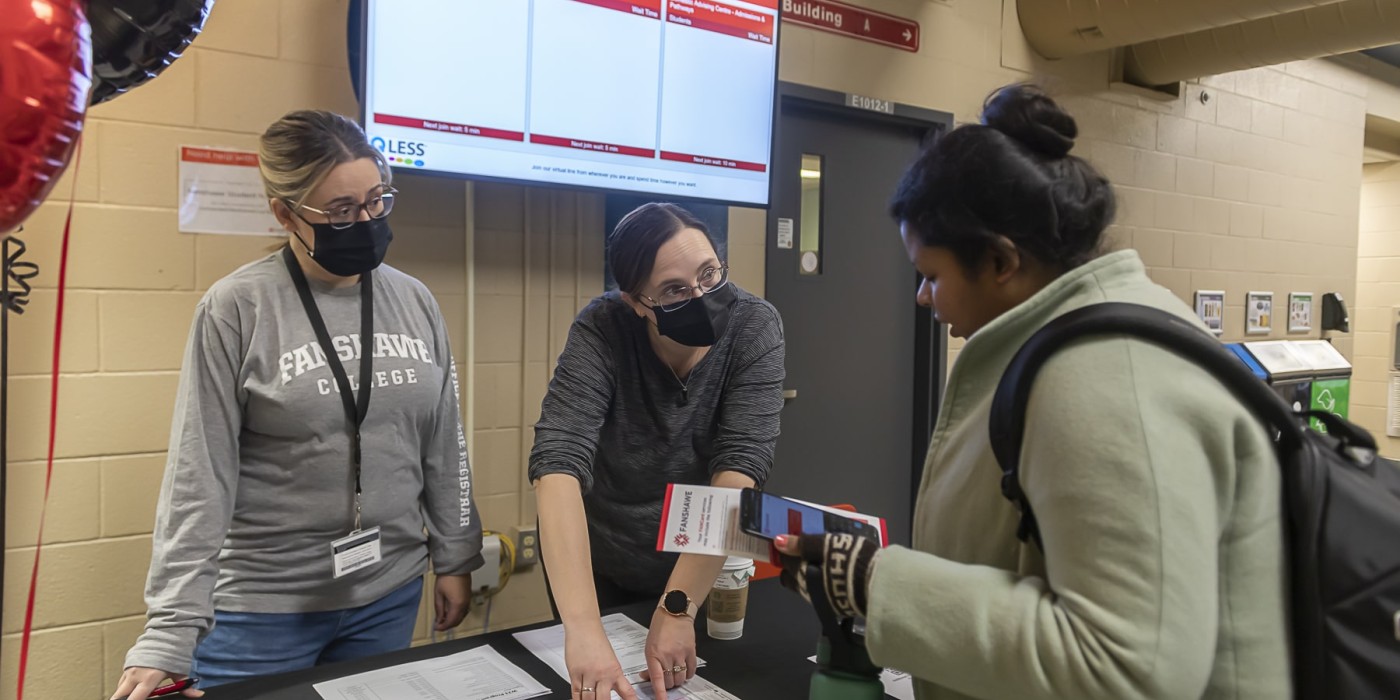two women pointing to locations on campus map for student to see