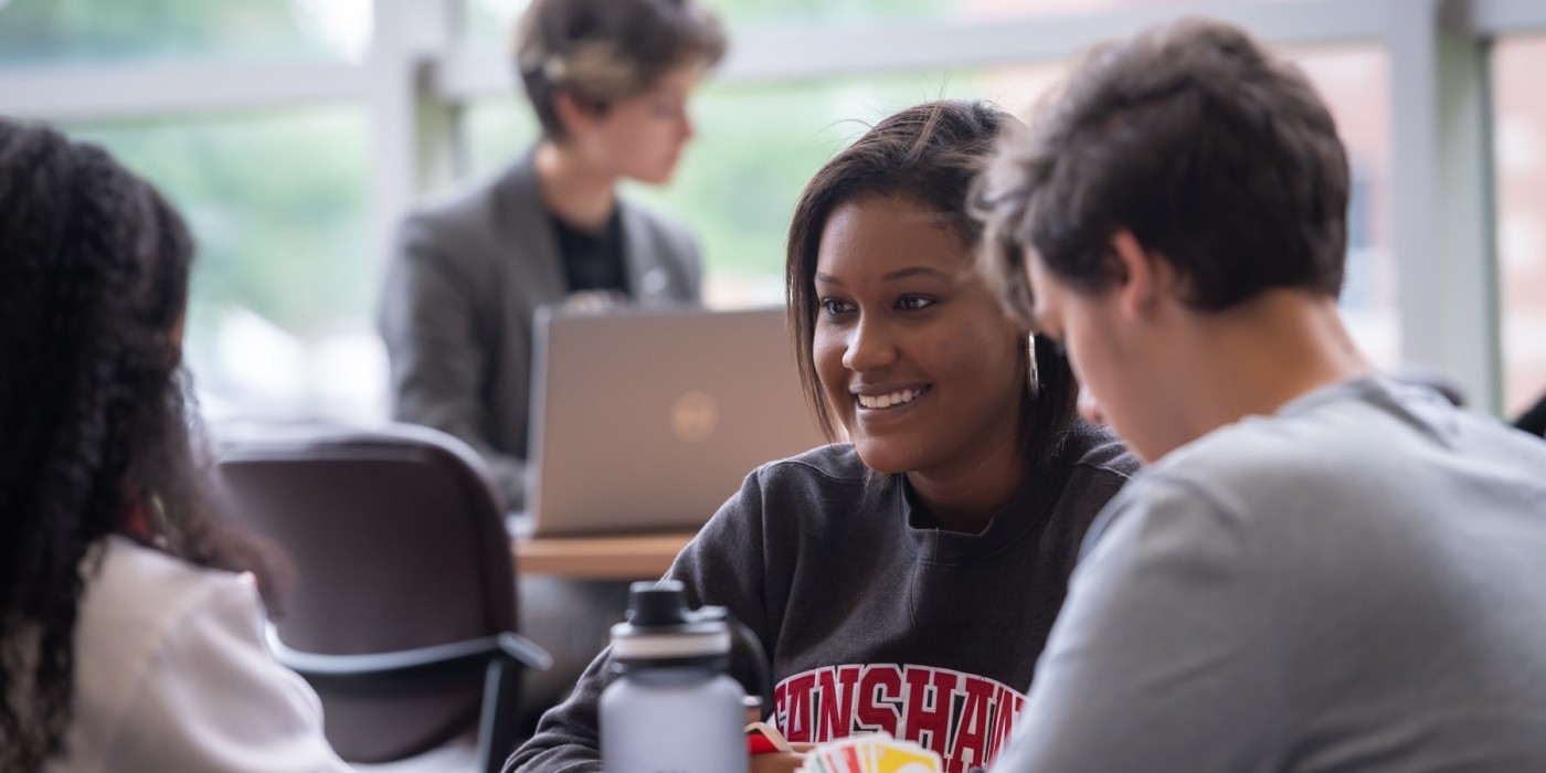 students sit around a table playing cards