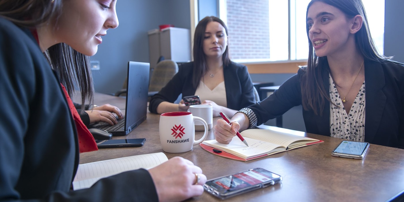 group of people sit around a table with notebooks