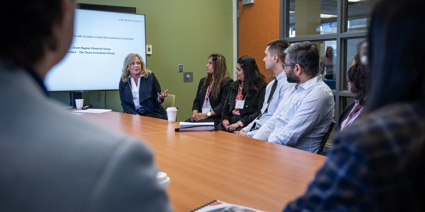 group of professionals sits around a table while woman speaks