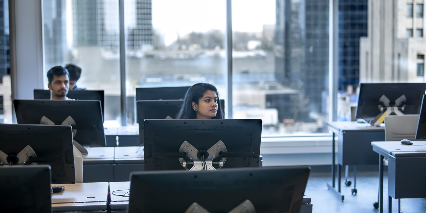 student sits at desk with large computer monitor in a classroom