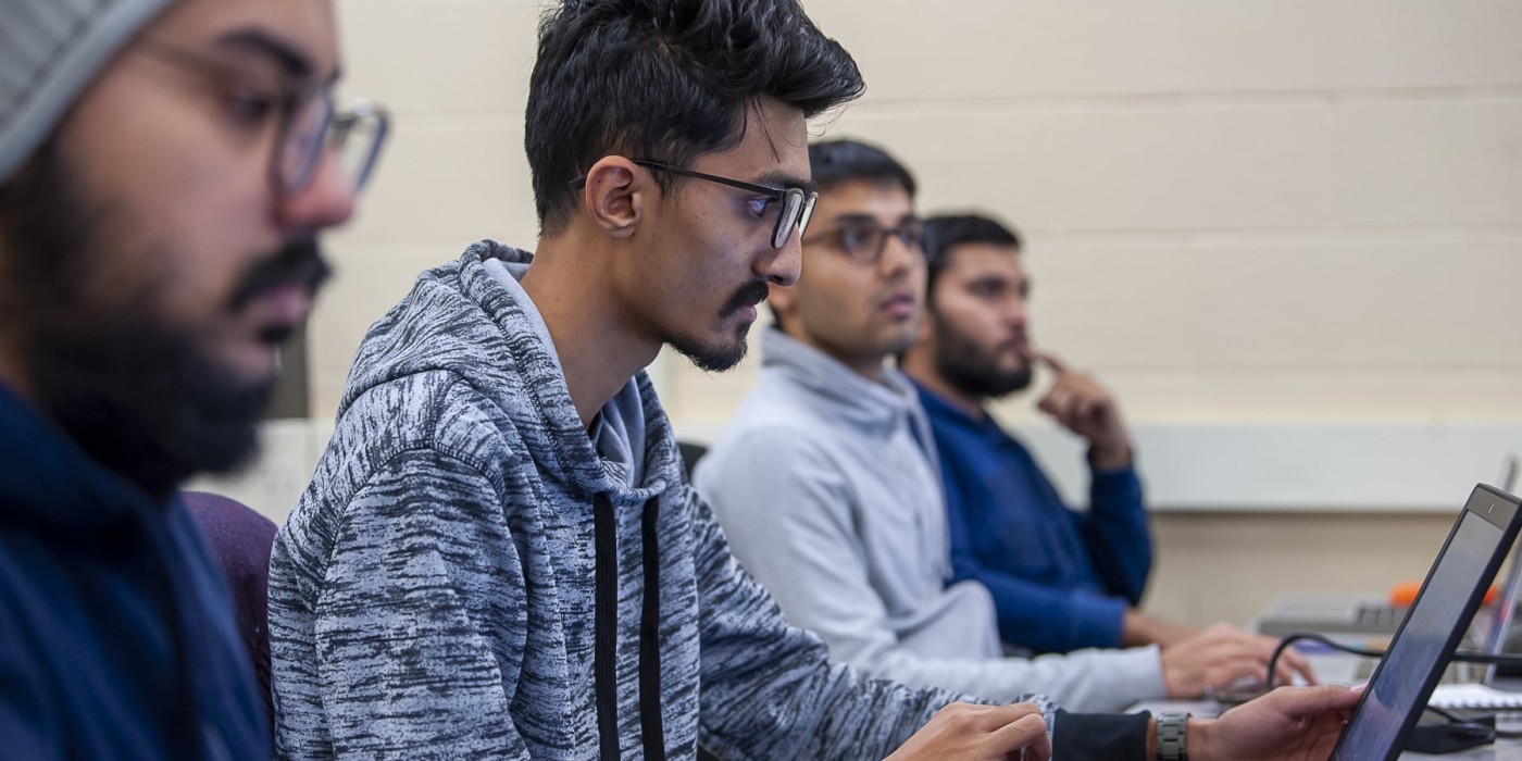 Technical systems analyst student sits looking at laptop